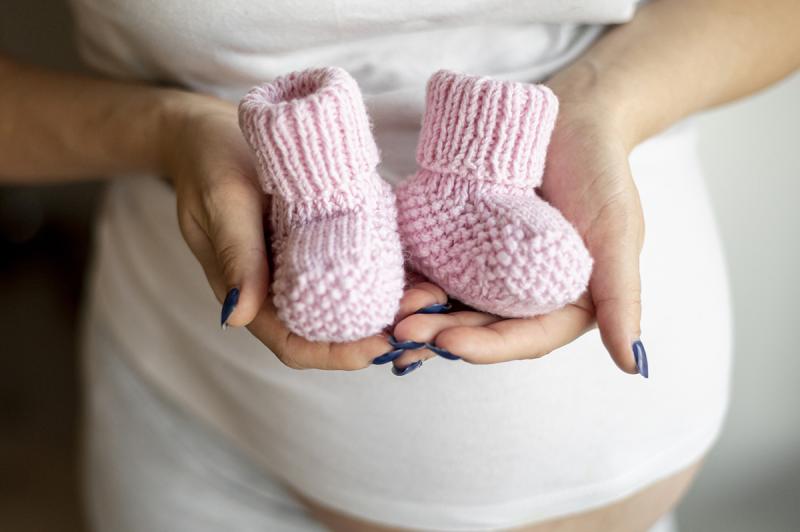 mujer embarazada sosteniendo zapatitos de bebé