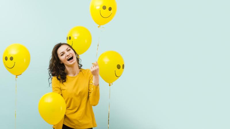 Mujer feliz con globos amarillos