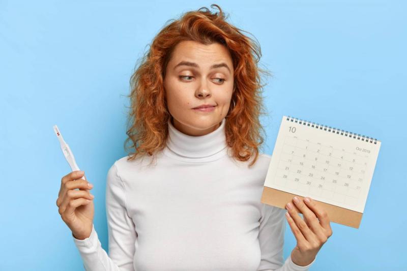 Mujer con un test de embarazo y un calendario