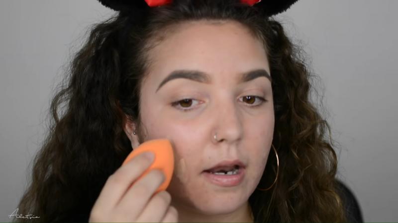 Poniendo base de maquillaje en la cara para tapar el acné