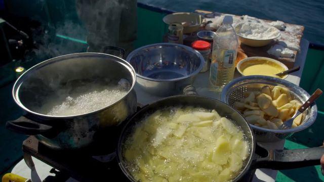 Merluza frita con papas fritas en compañía de amigos en medio del lago.
