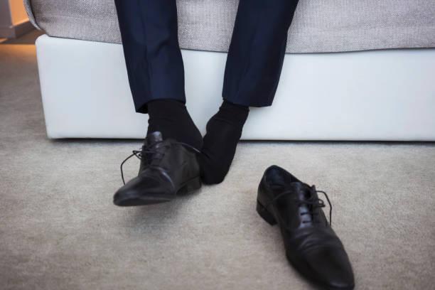 Hombre quitándose los zapatos. Créditos: iStock