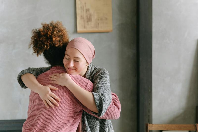 Mujer abraza a otra. Una tiene un pañuelo en la cabeza. Imagen referencial de paciente que tuvo cáncer. Créditos: Pexels