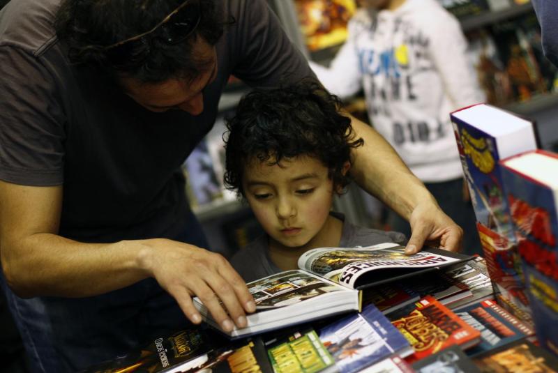 Hombre junto a un niño hojean novela gráfica / Agencia Uno