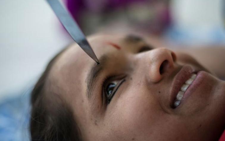 Joven delinea sus ojos con cuchillos mientras hace yoga 